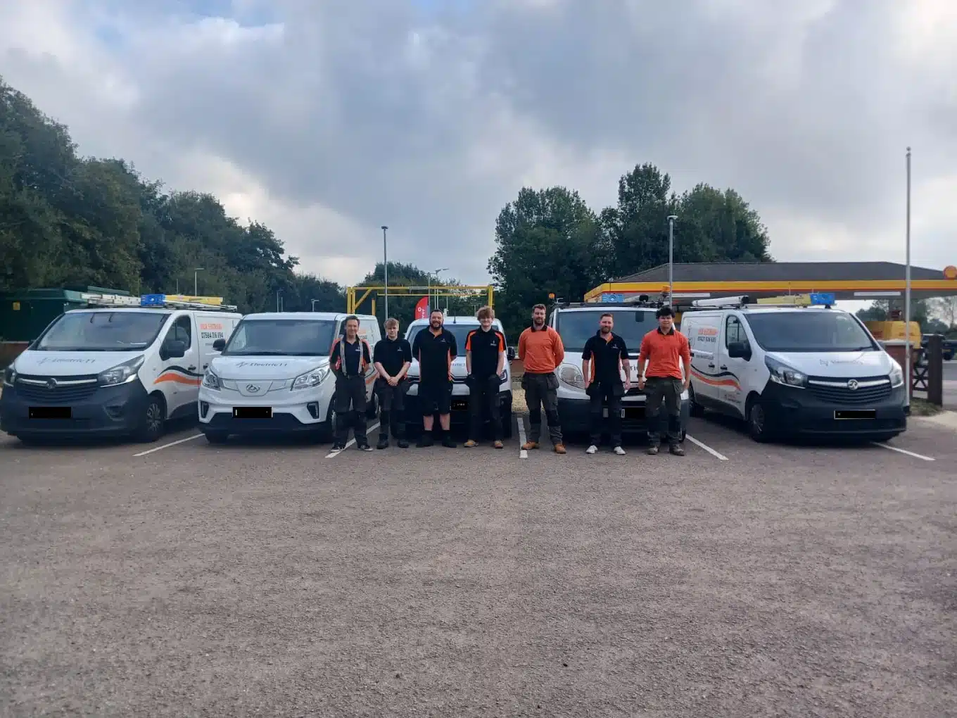 Electric11 team standing beside fleet of electrician service vans