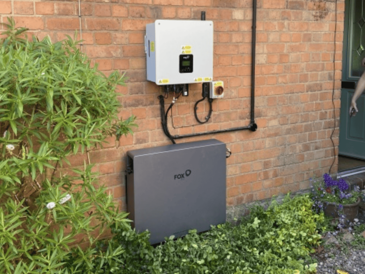 Home battery storage and solar inverter installed on exterior brick wall