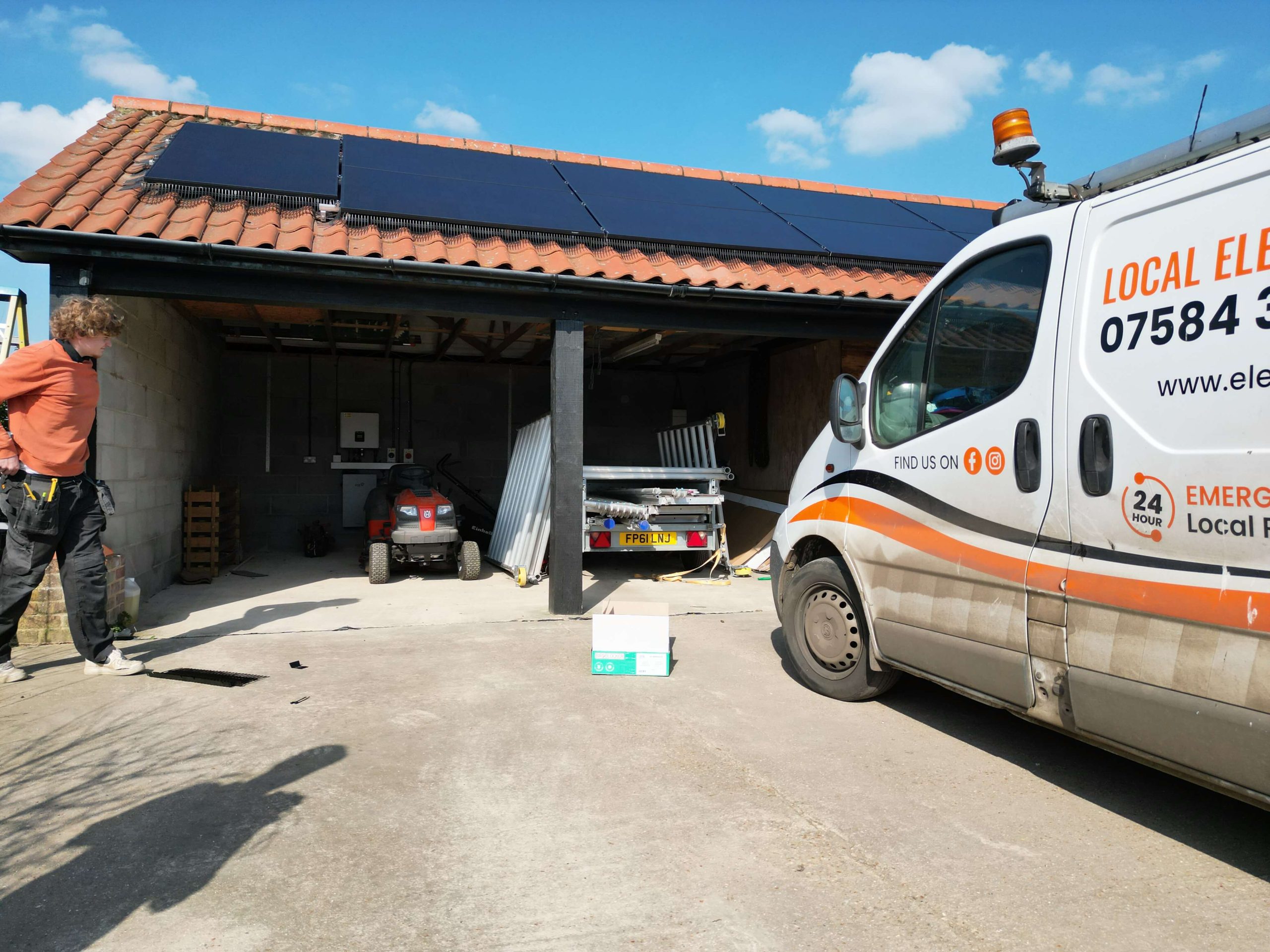 Electric11 van parked beside a garage with rooftop solar panels during installation