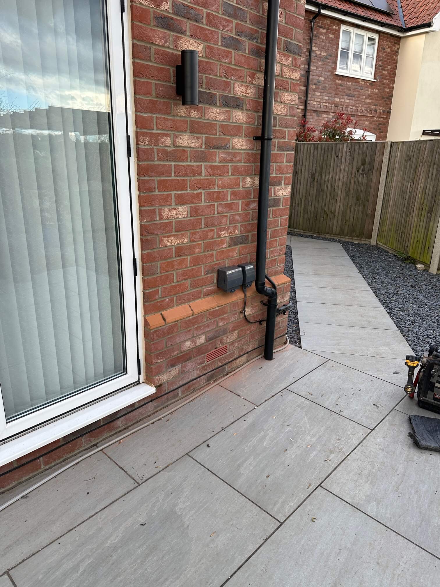 Two black IP-rated outdoor sockets installed beside a rainwater downpipe on the brick wall.