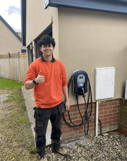 Electric11 electrician beside a newly installed wall-mounted home EV charger.