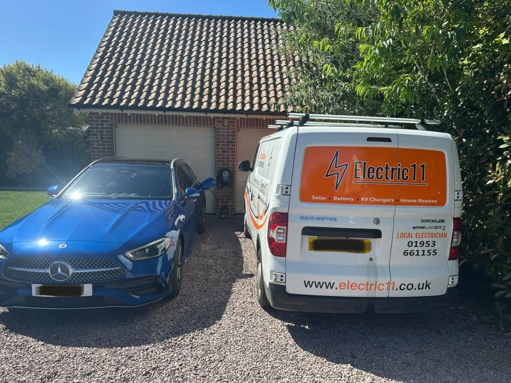 Electric11 service van beside an electric car connected to a home EV charger.