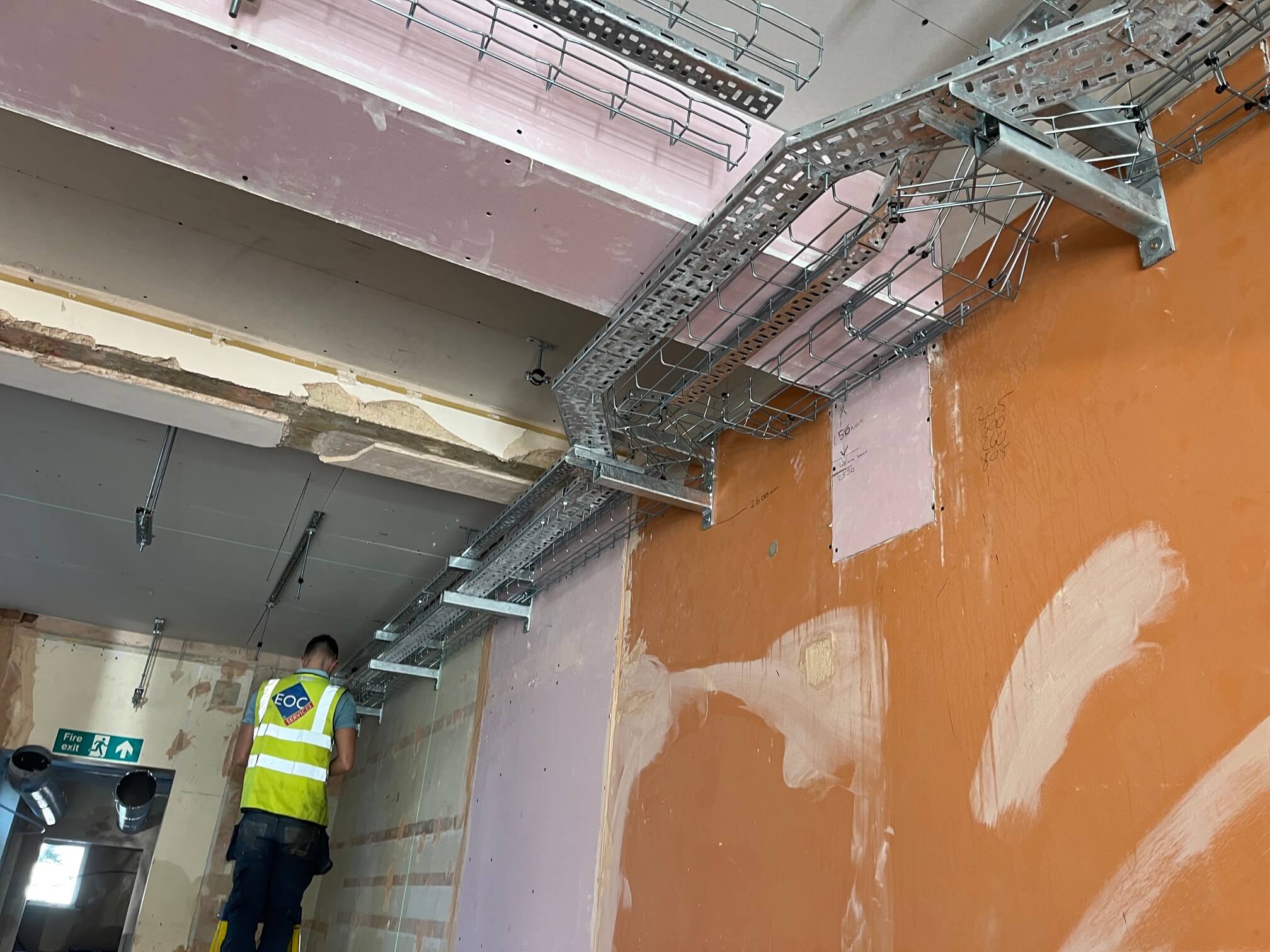 Electrician working beside cable tray at the Wymondham Banking Hub