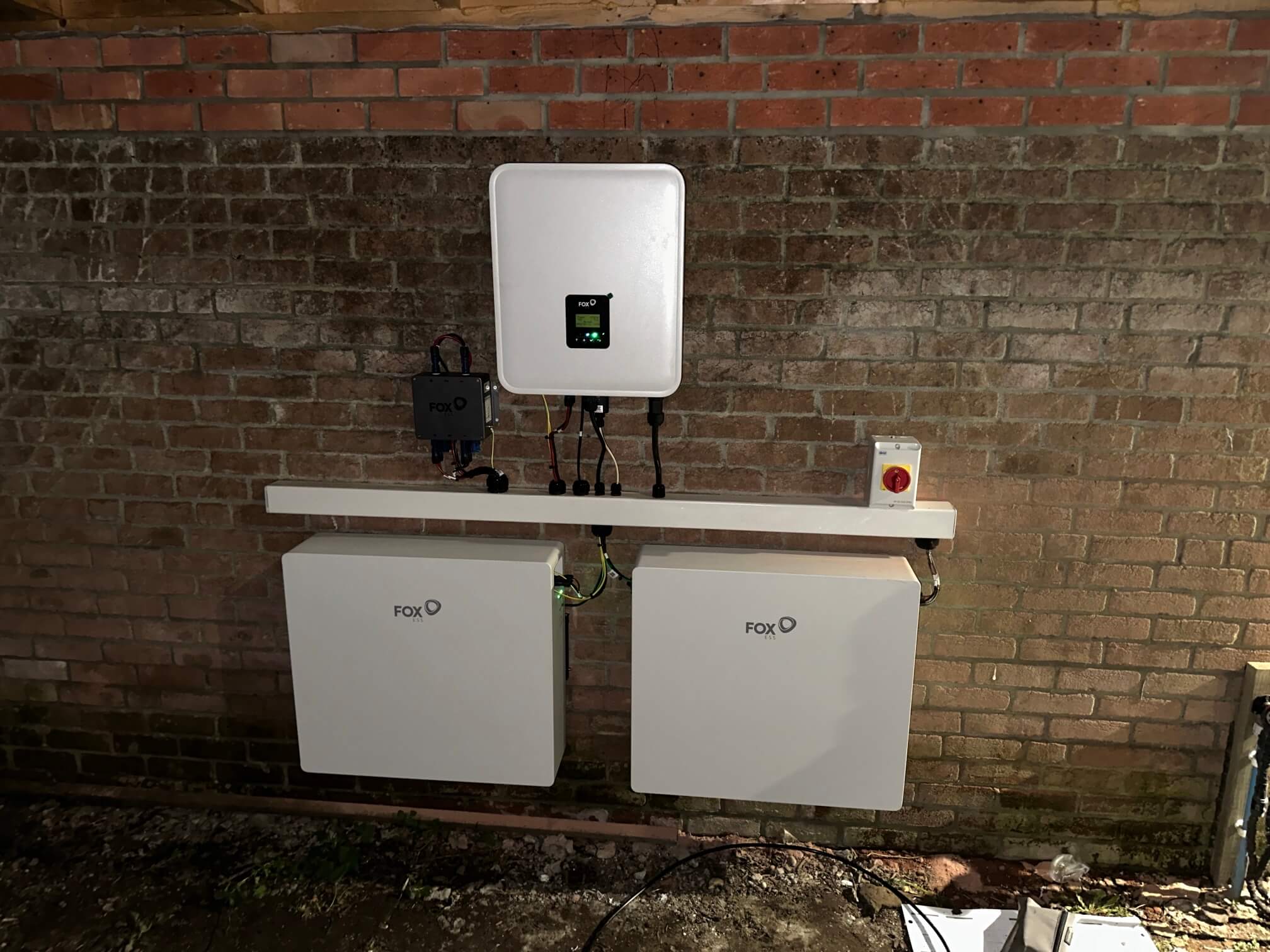 FOX ESS hybrid inverter and two EP12 Plus batteries mounted on a brick wall