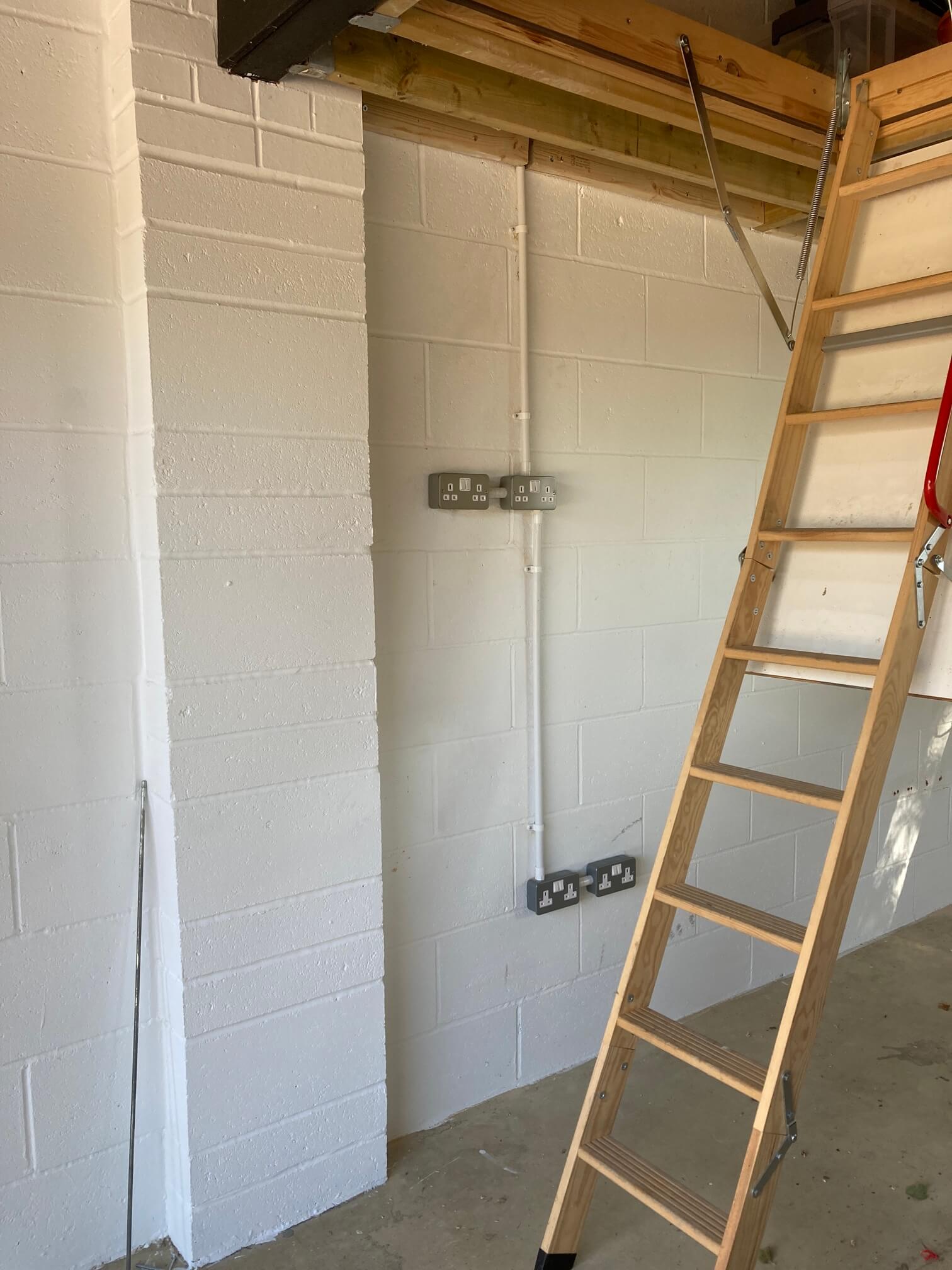Galvanised double sockets with white surface conduit on a garage wall