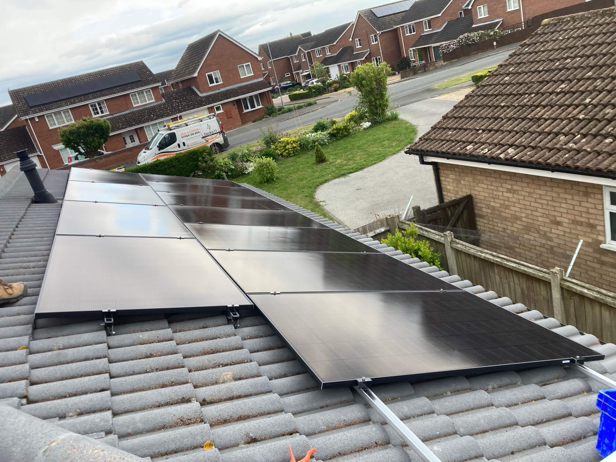 Close view of 16 black solar panels mounted on a tiled bungalow roof