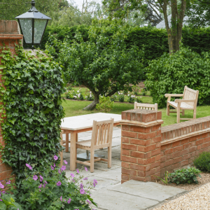 Black lantern-style garden light beside a brick-walled patio with outdoor seating.