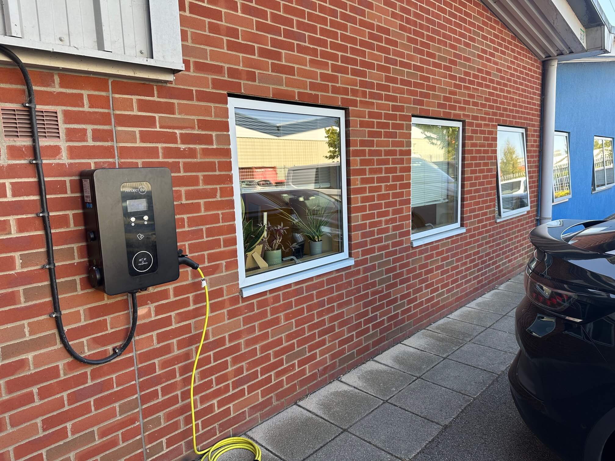 Wall-mounted EV charger beside parking spaces at a Wymondham business