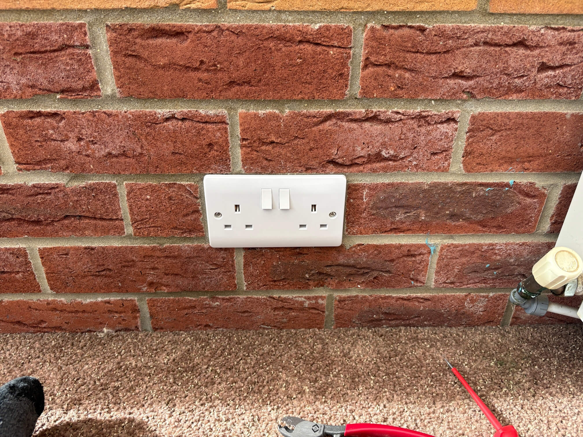 White double socket on a brick wall in the conservatory