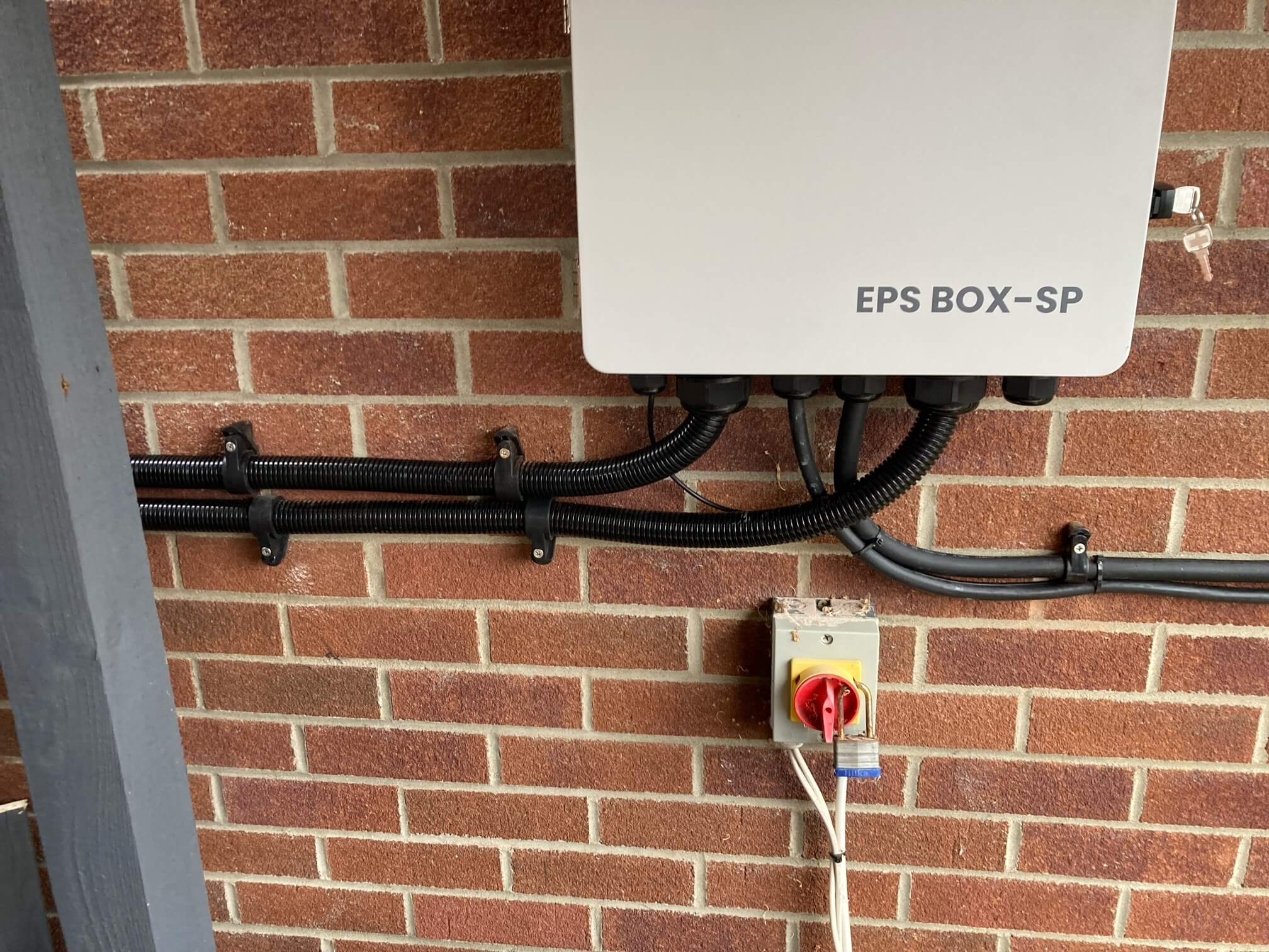Wall-mounted EPS BOX-SP enclosure with external cable routes and a rotary isolator below