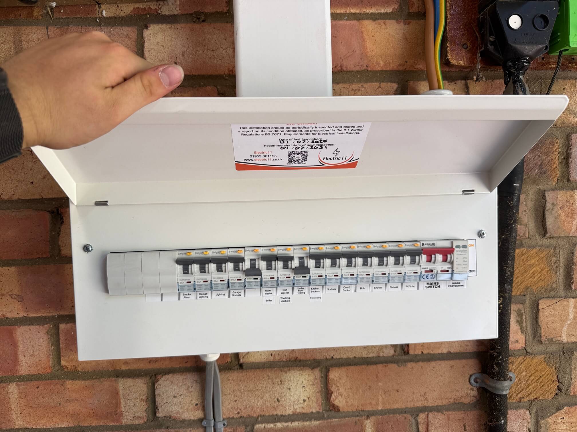 Replacement consumer unit with labelled circuits and an Electric11 inspection sticker at the Thetford property.