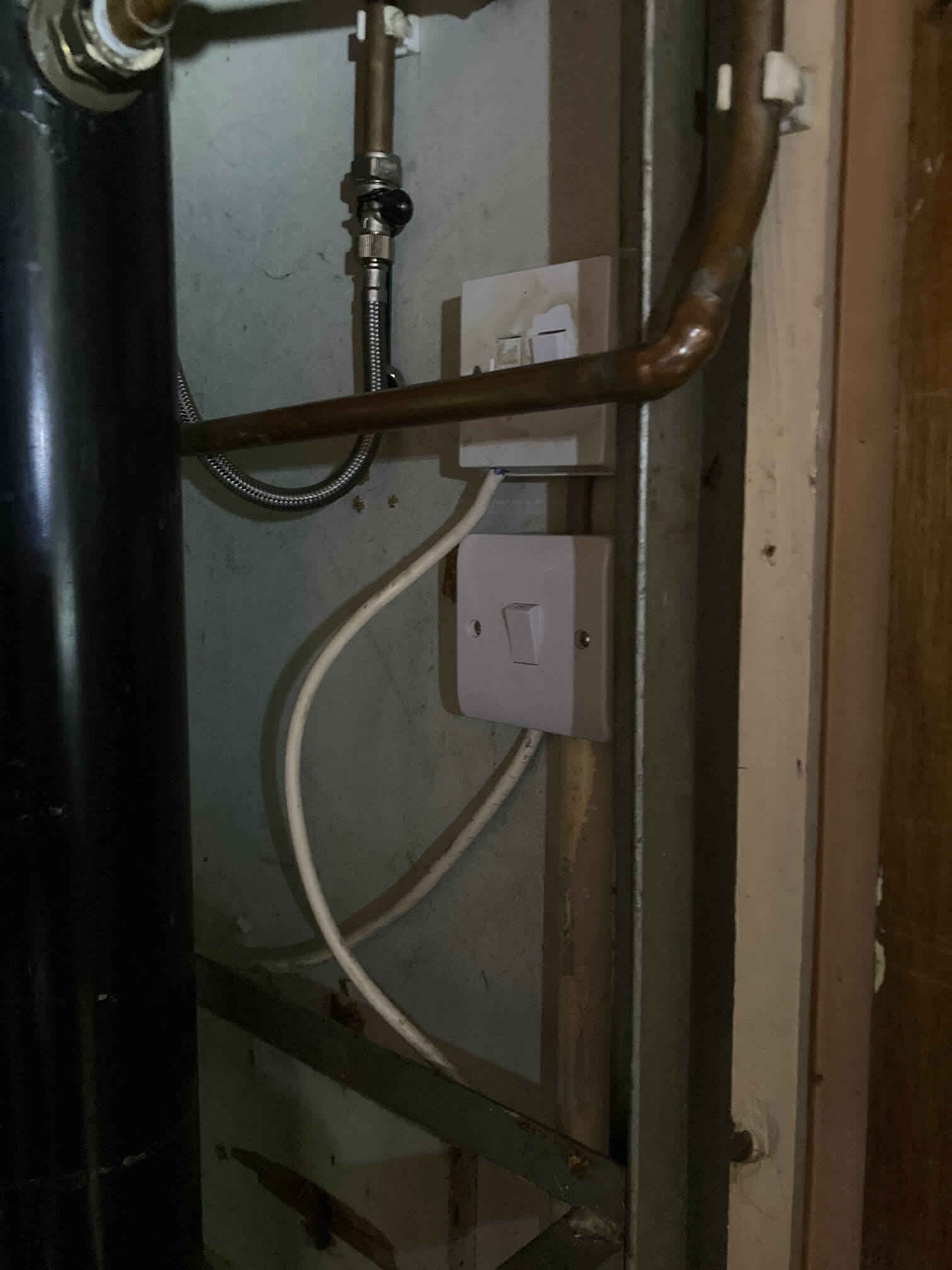 White electrical accessories and cabling beside pipework in the immersion cupboard